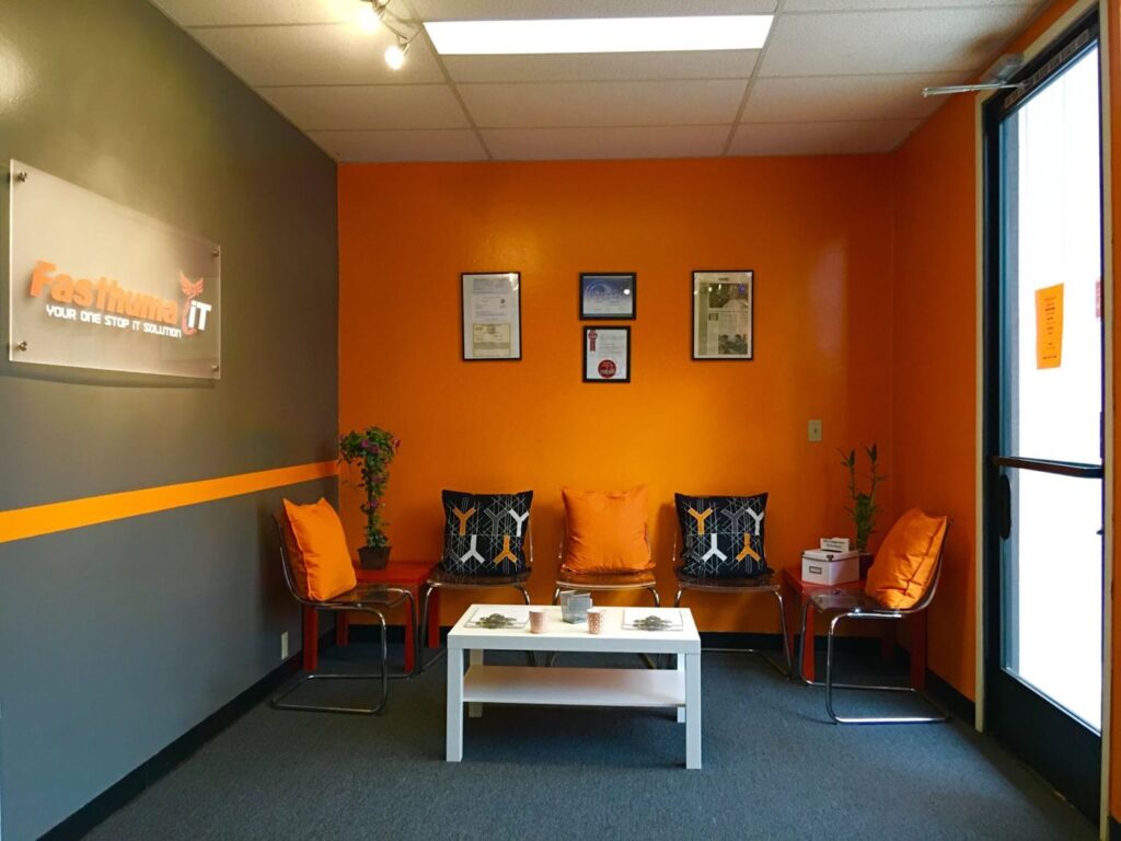 Fasthuma iT reception area in Fremont with orange walls, orange chairs and the Fasthuma iT logo sign